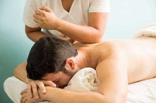 Therapeutic massage therapist providing a relaxing back massage to a client lying face down on a massage table.